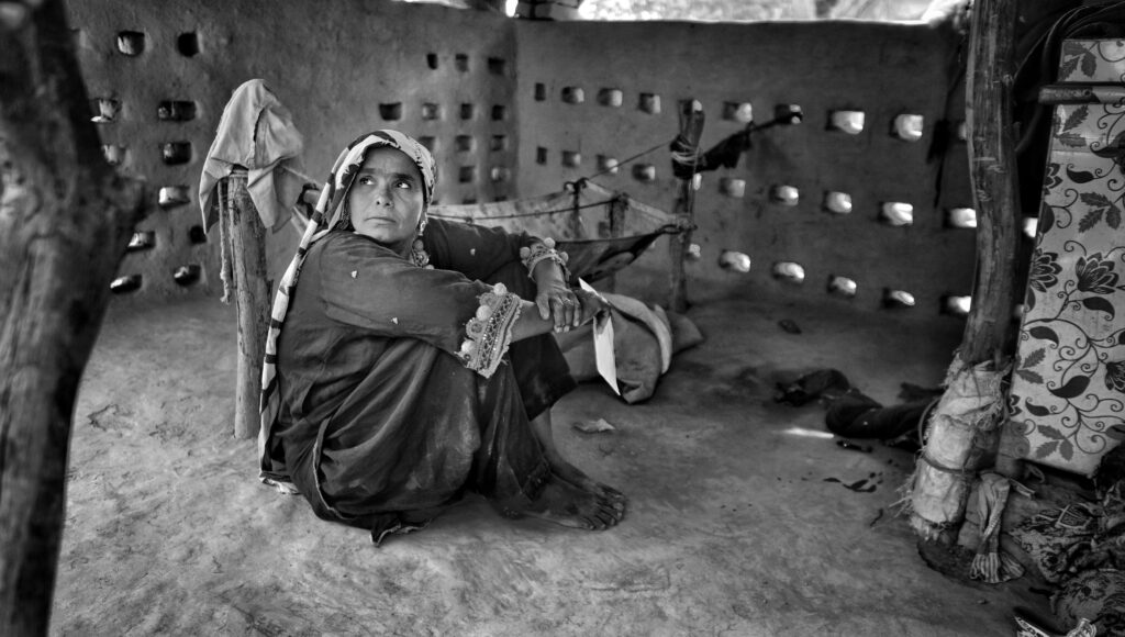 A woman sits thoughtfully in a rustic interior, reflecting cultural heritage.