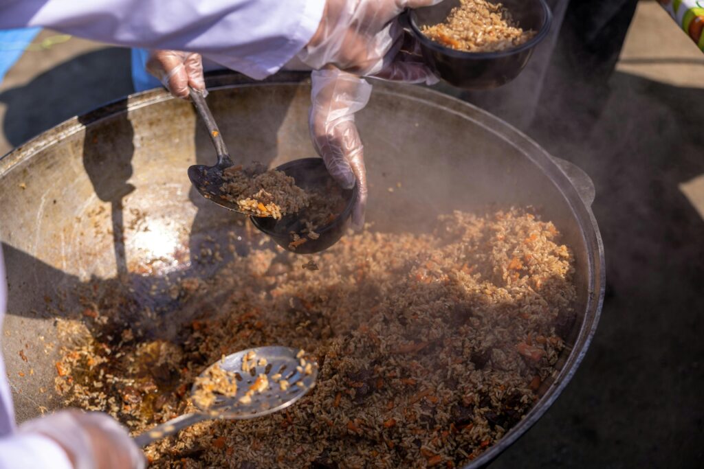 DISTRIBUTION OF HOT FOOD AND DRY RATION Hands scoop rice dish into bowls, showcasing vibrant street food preparation.